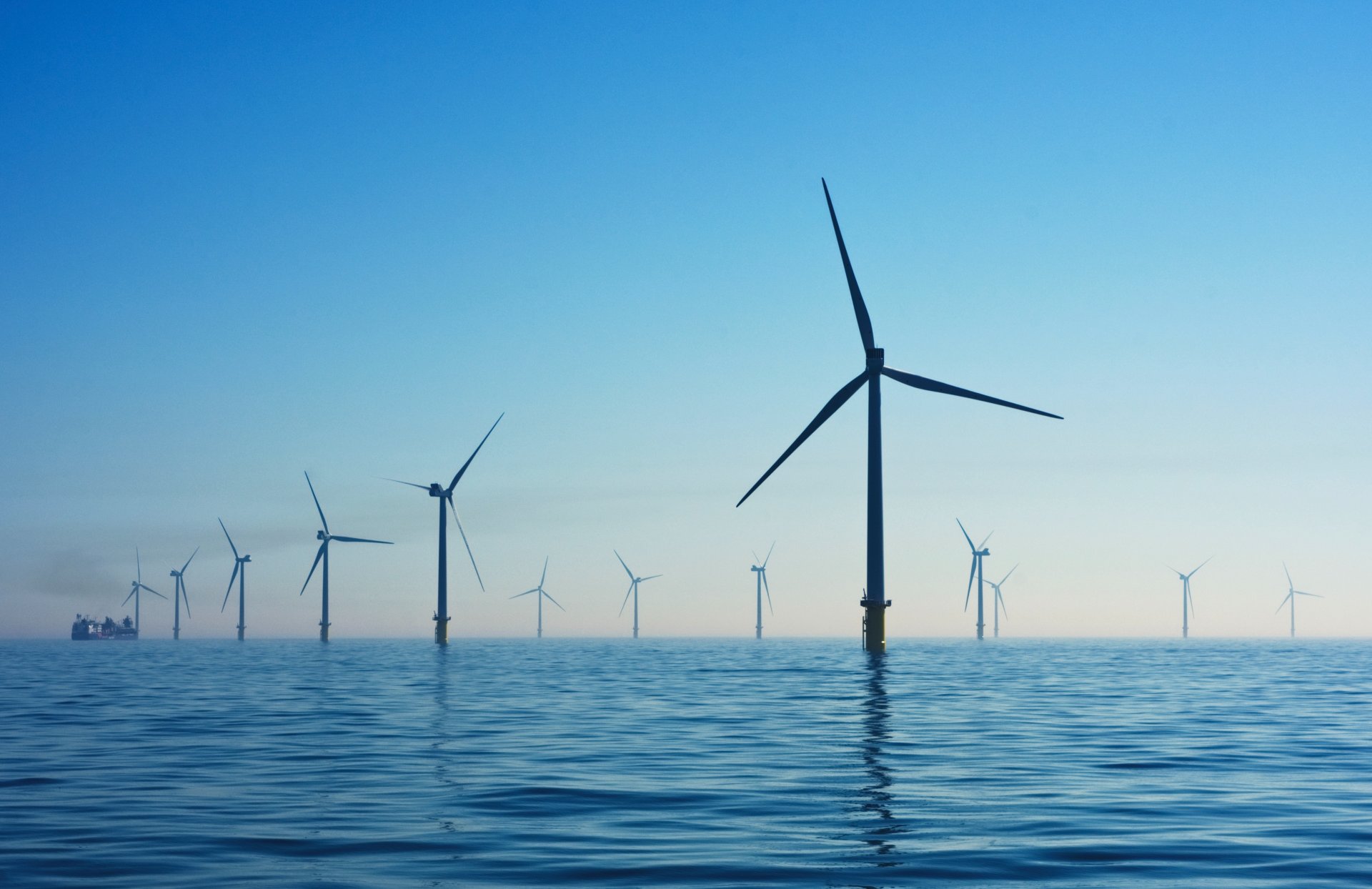 Autamme asiakkaitamme monipuolisesti energia-alan infran ja verkon kehittämiseen liittyvillä hankkeilla - sekä tuemme heidän onnistumisiaan energian erikoisosaamisellamme. Tuulivoima on yksi uusiutuvan energian lähteistä. Kuvassa tuulivoimaloita merellä auringonlaskun jälkeen.
